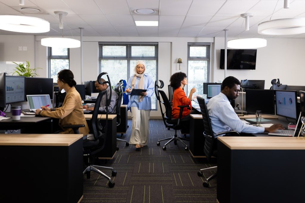 Diverse female and male businesspeople working in office with open space